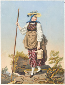 Jeune femme avançant sur un sol pierreux en costume de l’Oberhasli, avec foulard, chapeau de paille, baton et seau à lait